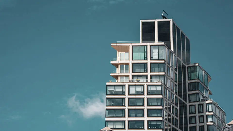 The upper floors of a residential high-rise with terraces, against a clear sky.